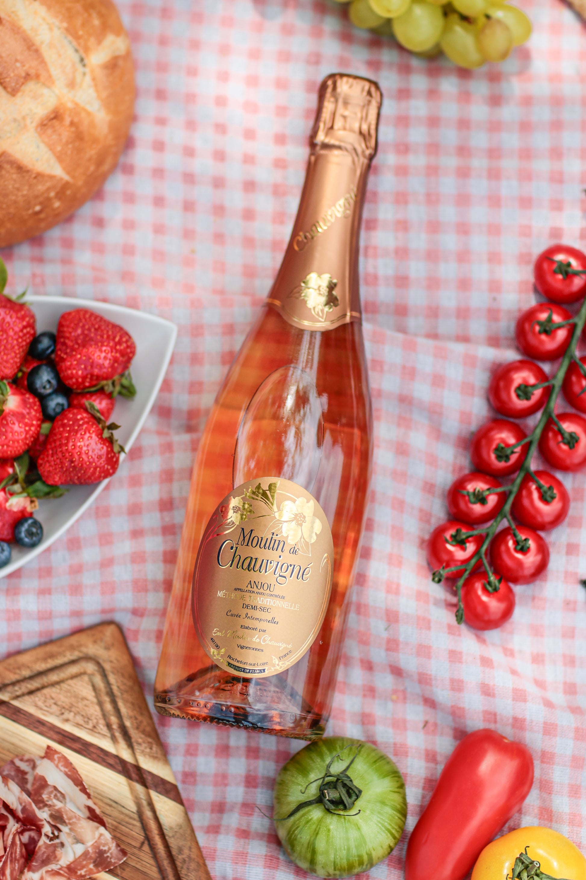 Bouteille de vin effervescent rosé demi-sec Moulin de Chauvigné AOP Anjou, méthode traditionnelle, présentée lors d’un pique-nique gourmand avec fruits, pain et charcuterie, vin de la Vallée de la Loire