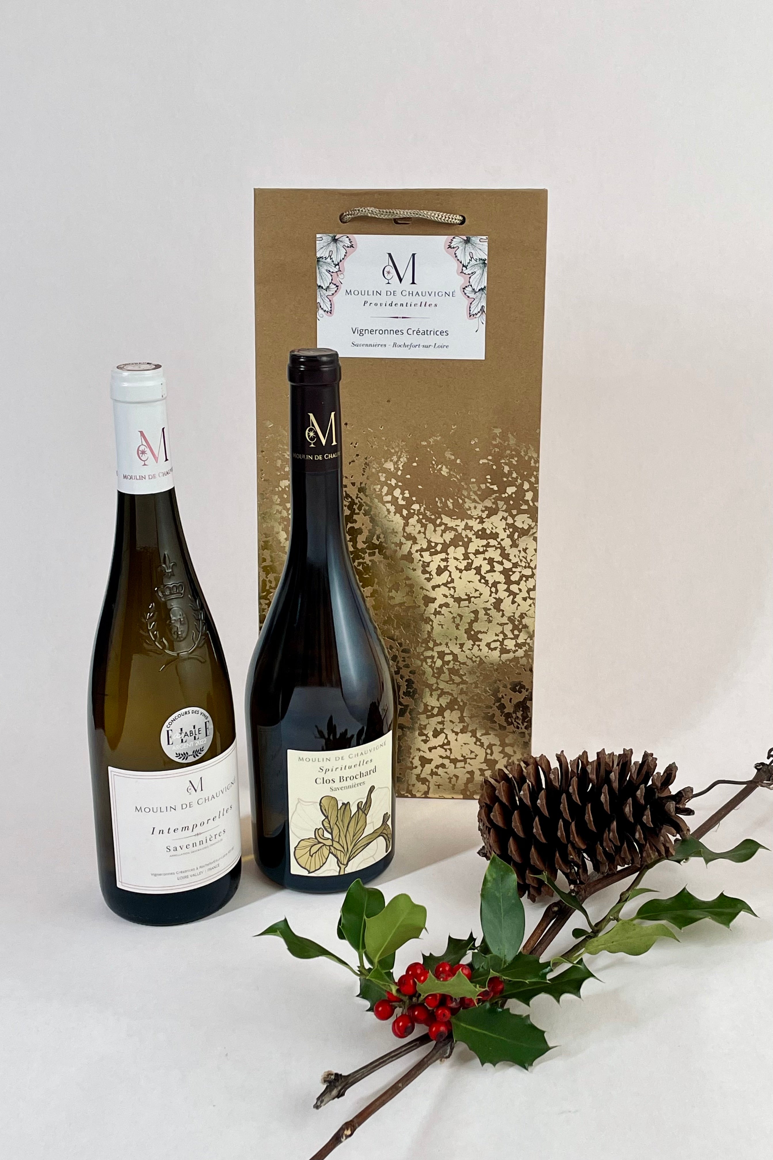 Deux bouteilles de vin de Savennières du Moulin de Chauvigné présentées avec un sac cadeau, accompagnées d’une pomme de pin et d’une branche de houx