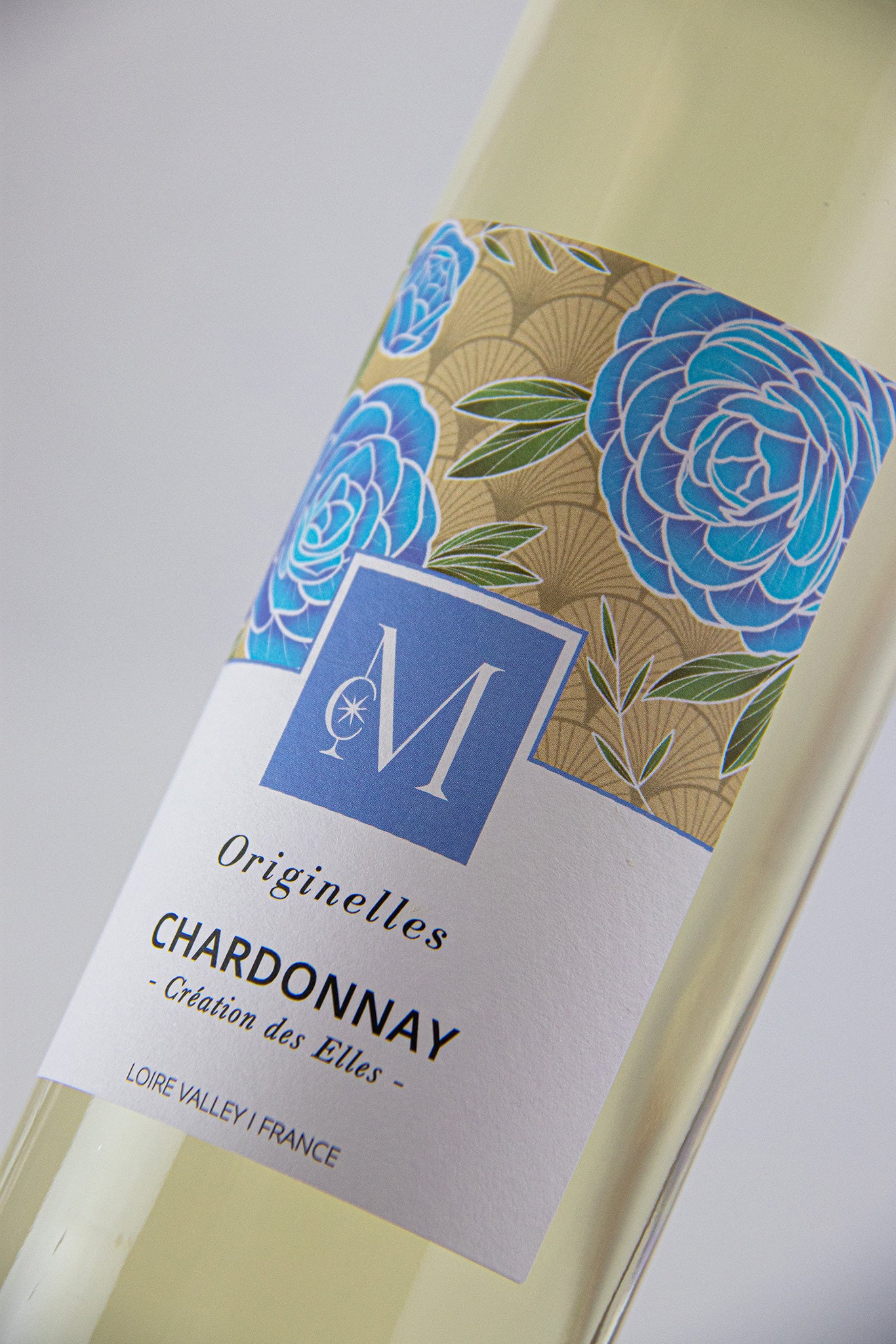 Gros plan sur l’étiquette du vin blanc Originelles Chardonnay du Moulin de Chauvigné, ornée de motifs floraux bleus